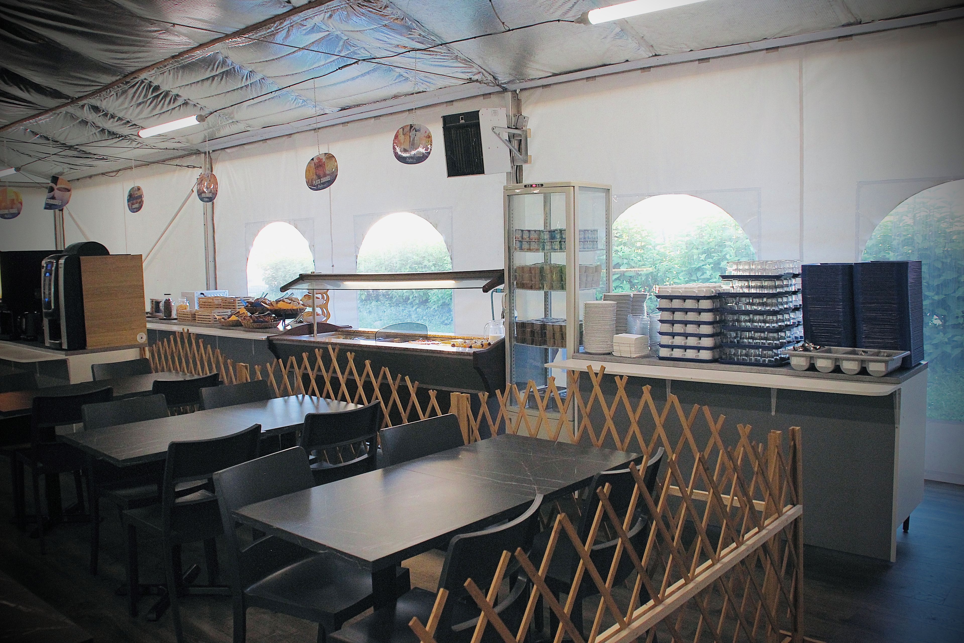 A restaurant interior with tables, chairs, and a counter with food items.