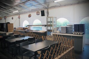 A restaurant interior with tables, chairs, and a counter with food items. - Olydea Les Epesses (Les Epesses)