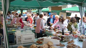 A bustling outdoor market with various food stalls under green canopies. - Hostal Casa Manolo (La Senia)