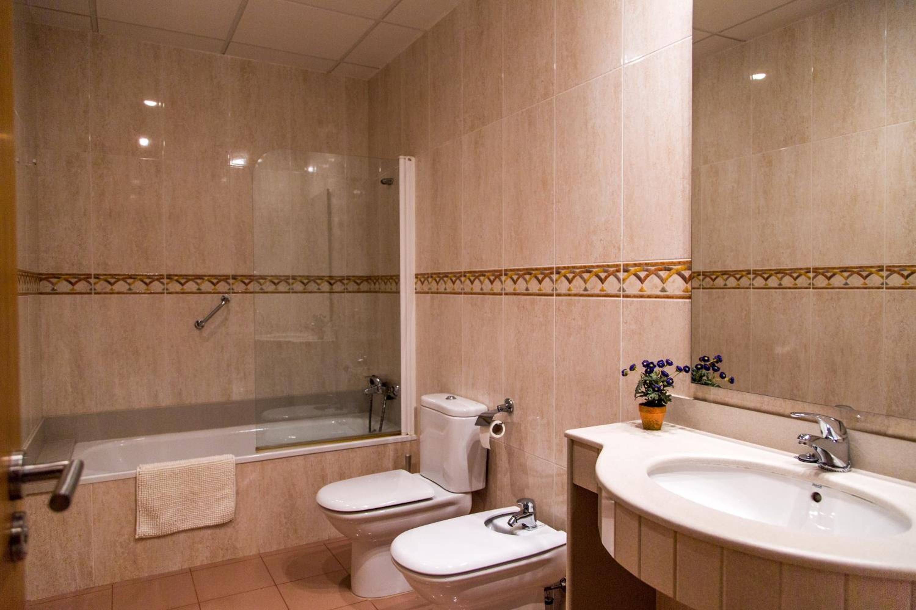 A bathroom with a bathtub, two toilets, a sink, and a shower.