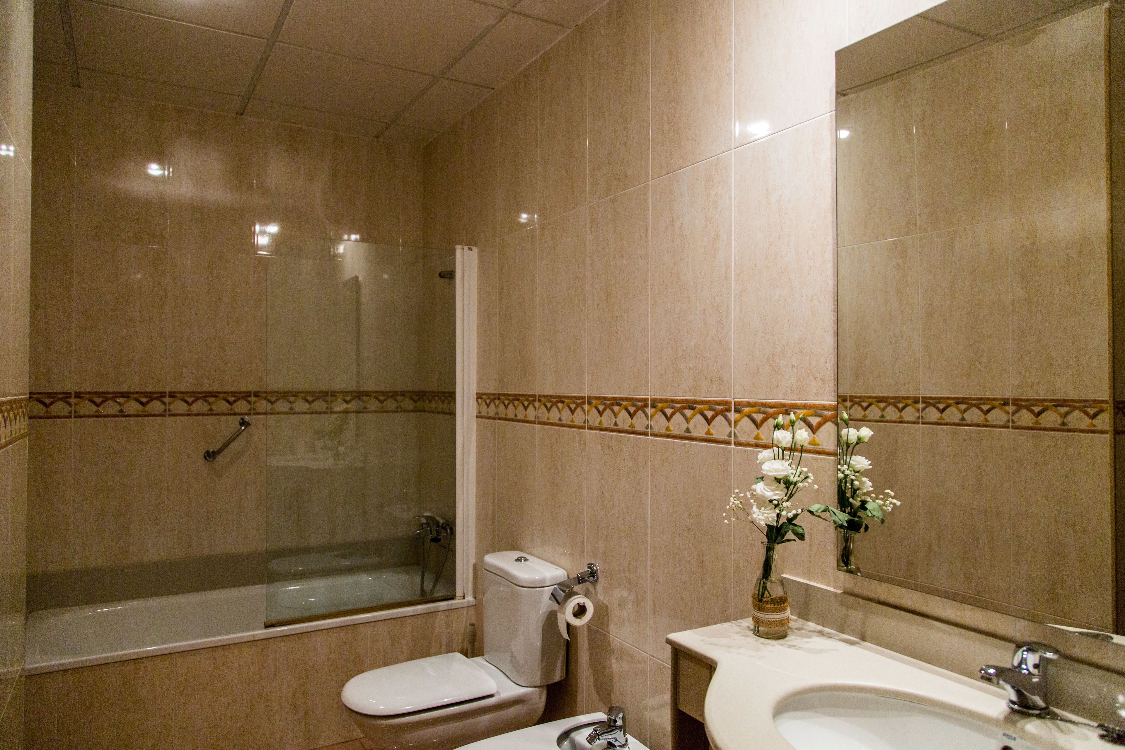 Un baño con bañera, inodoro, lavabo y espejo.