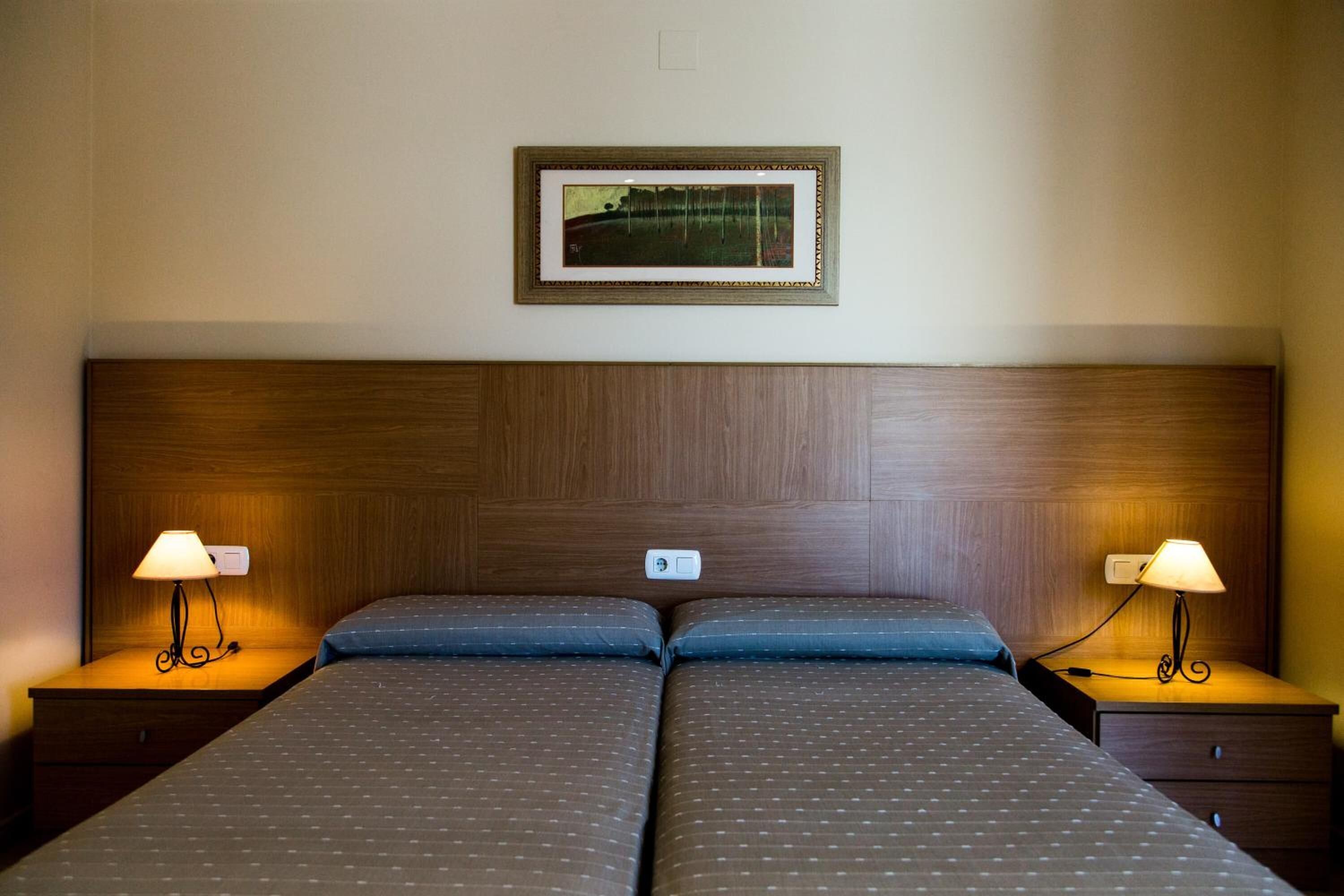 Un letto matrimoniale con testiera in legno, due comodini con lampade e un quadro appeso al muro.