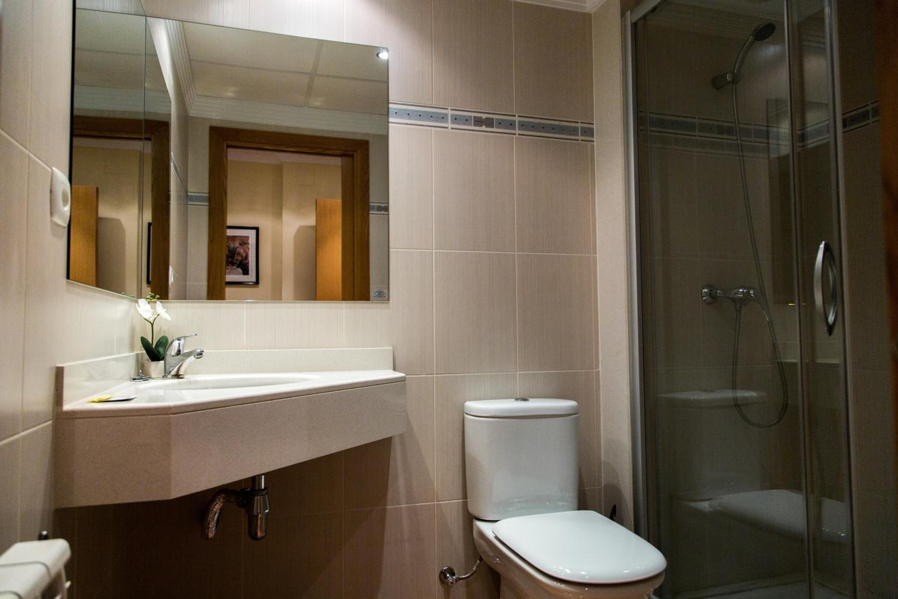 Un baño con lavamanos, inodoro y ducha con cerramiento de vidrio.
