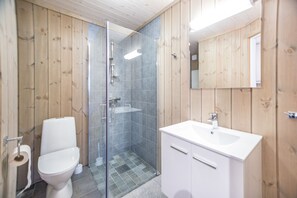 A modern bathroom with a glass-enclosed shower, a white toilet, and a white sink with a cabinet.