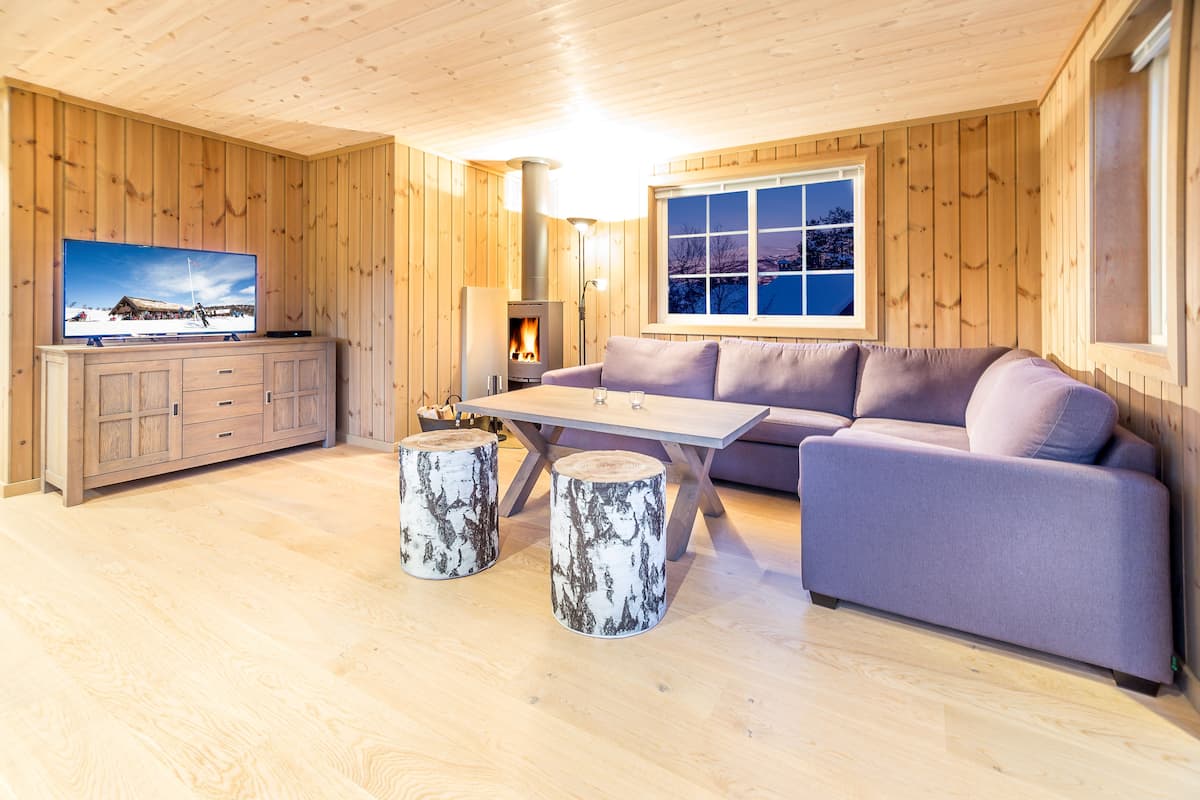 A cozy cabin interior with a wooden interior, a sofa, a table, and a television.