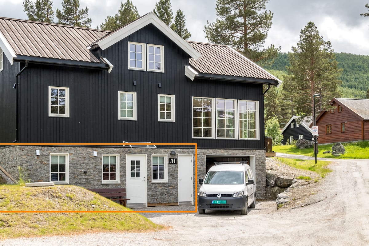 A two-story house with a stone foundation, multiple windows, and a garage.