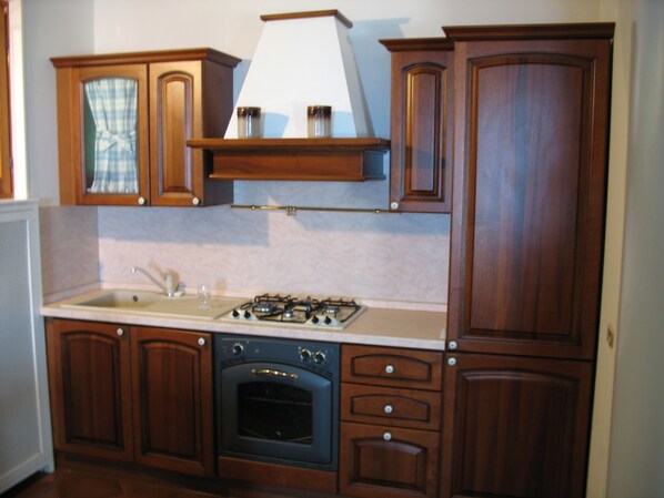 Una cocina con gabinetes de madera, estufa y lavaplatos.