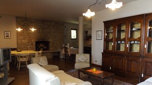 A living room with a stone fireplace, a dining area, and a kitchen. - Villa Bardino (Torri del Benaco)