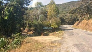 Un panneau de signalisation indiquant « Coolwaters » dans un environnement rural, avec un chemin de terre et de la végétation.