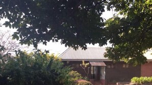 Une maison avec un toit en pente, entourée d’une pelouse bien entretenue et d’un feuillage dense.