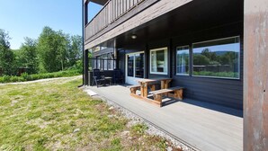En moderne bygning med træterrasse, udendørs siddepladser og store vinduer.