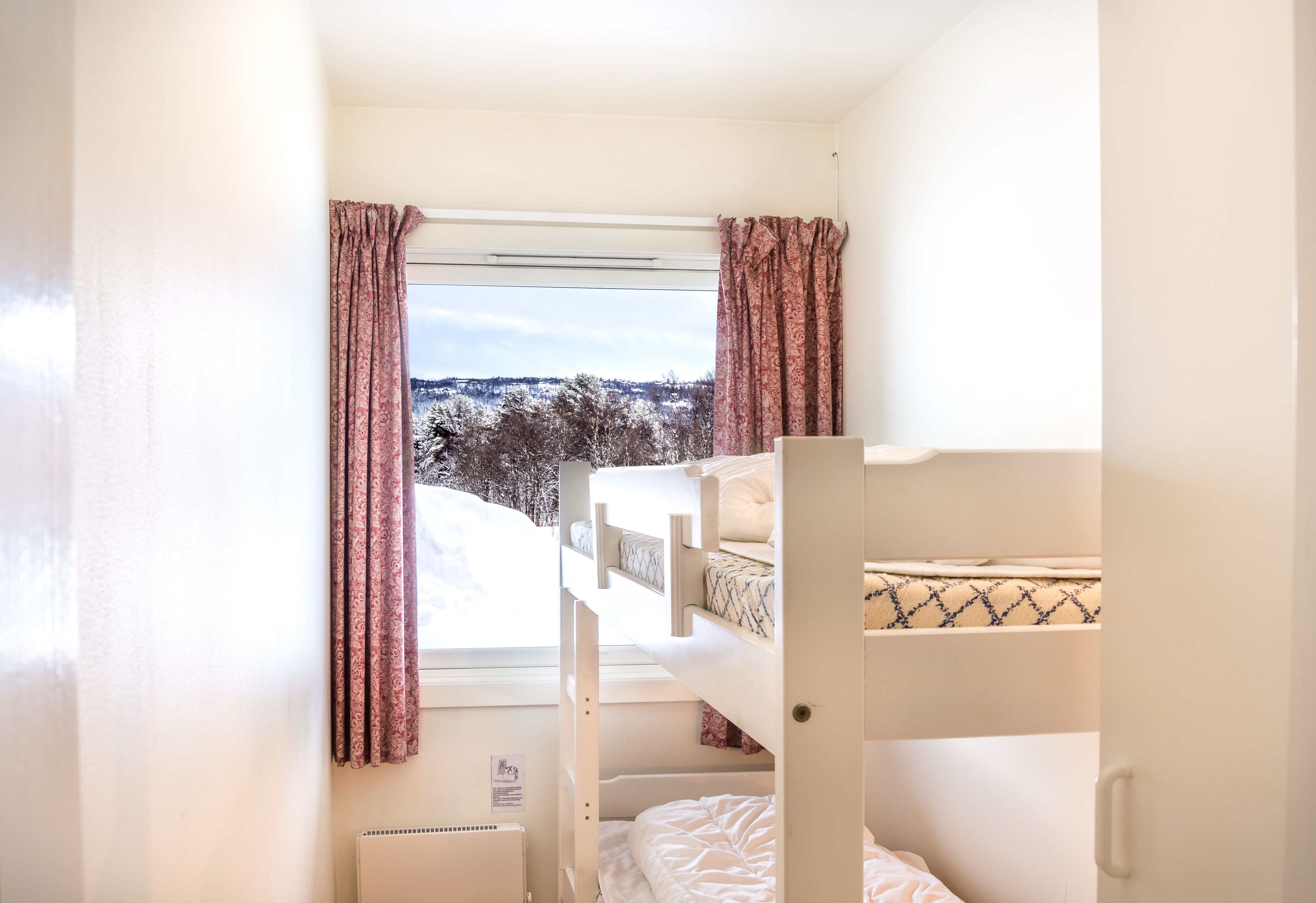 A bunk bed room with a window view of snow-covered trees.