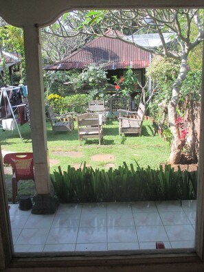 A patio area with a wooden table and chairs, surrounded by potted plants and a small garden. - ESA di Kubu Homestay (Sawan)