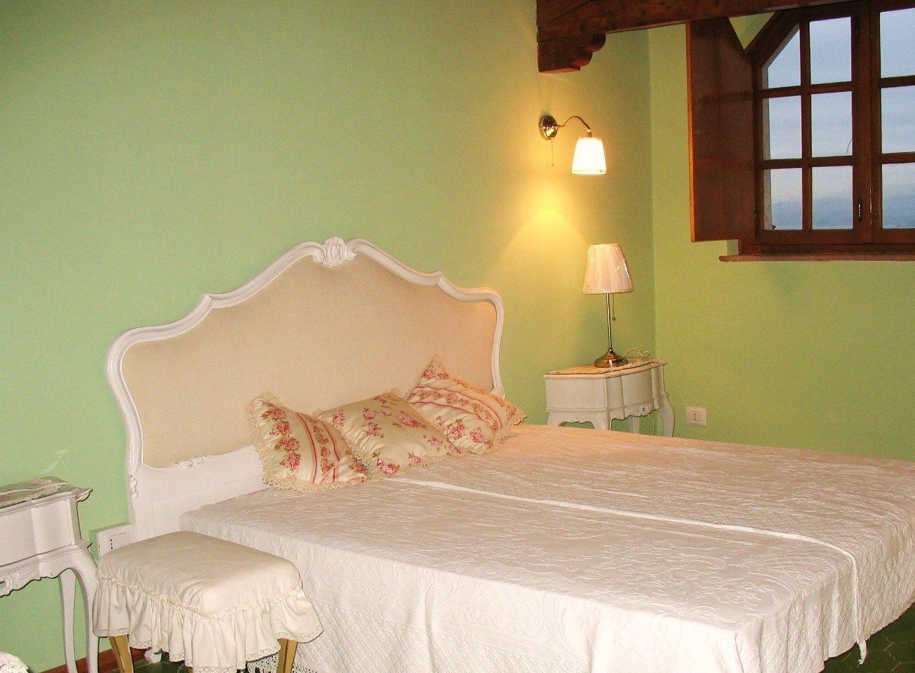 A bedroom with a bed, bedside tables, a lamp, and a window.