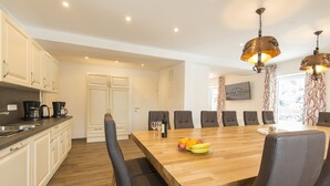 A modern kitchen with white cabinets, a wooden dining table, and black chairs.