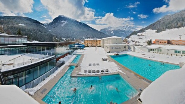 A resort with two swimming pools surrounded by snow-covered mountains.