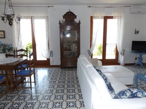 Una sala de estar con suelo estampado, un sofá blanco, un mueble de madera y un televisor sobre un soporte azul.