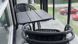 A balcony with a table and chairs, overlooking a road with cars and greenery. - Slåttastølen Leiligheter by Geilolia (Hol)