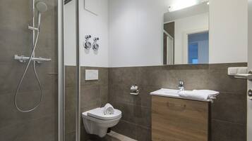 Une salle de bain moderne avec une douche à parois de verre, des toilettes et un meuble-lavabo avec un miroir.