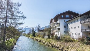 Une rivière qui longe un immeuble doté de balcons, avec une montagne en arrière-plan.