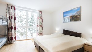 Une chambre à coucher avec un grand lit, une table de chevet, une fenêtre avec des rideaux et un tableau au mur.