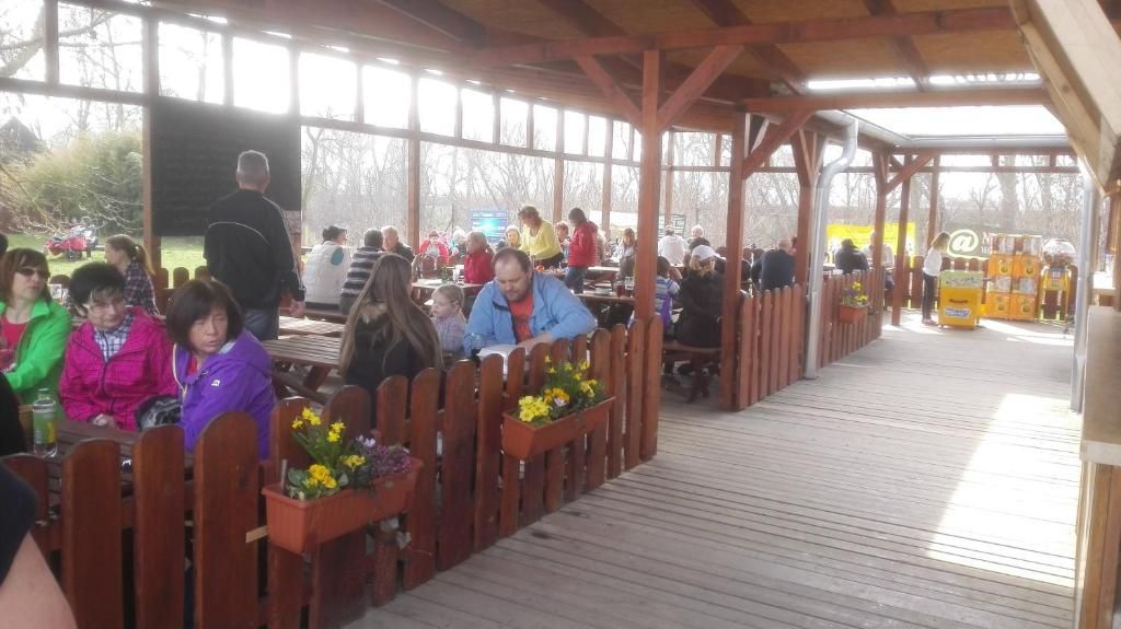 An outdoor covered seating area with wooden benches and flower planters.