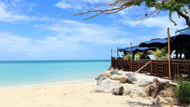 A beach with a wooden structure and umbrellas, overlooking a clear blue sea. - Rooms Boutique by Annie's (Cabo Rojo)