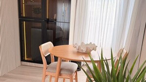 A dining area with a wooden table and chairs, a potted plant, and a black-framed glass door. - Rooms Boutique by Annie's (Cabo Rojo)