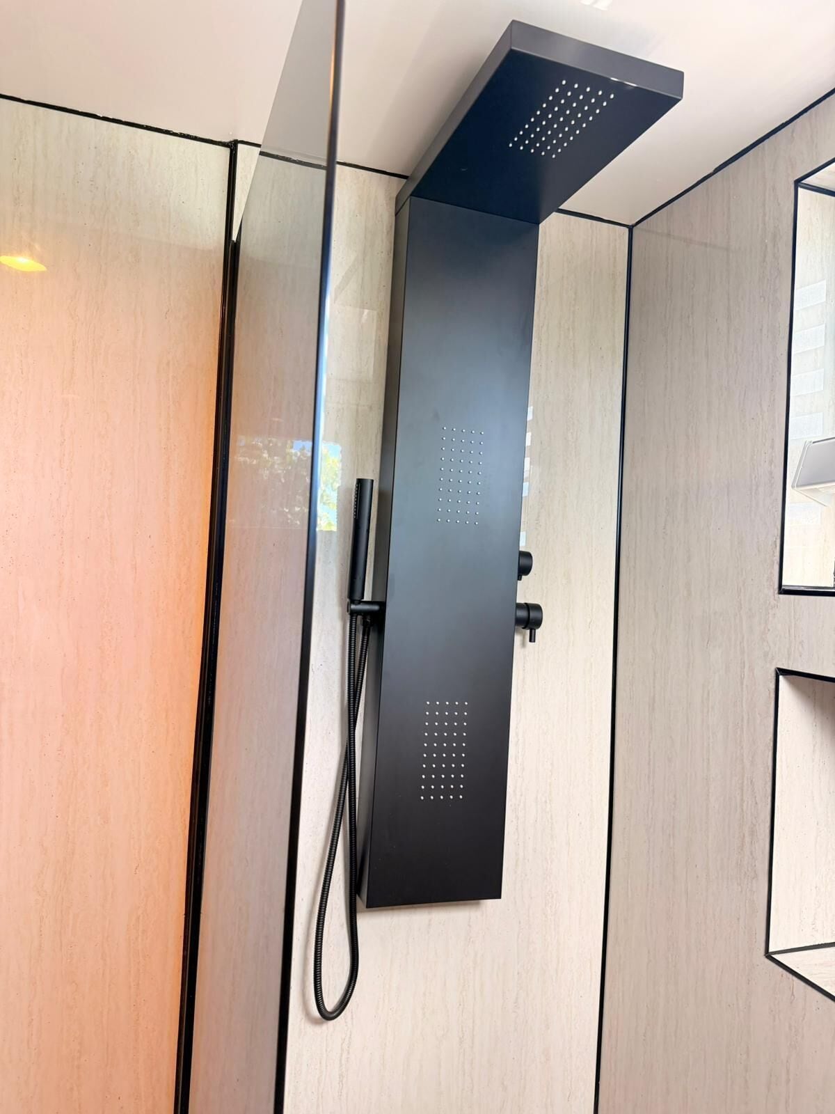 A modern shower enclosure with a sleek black design, a handheld showerhead, and a control panel.