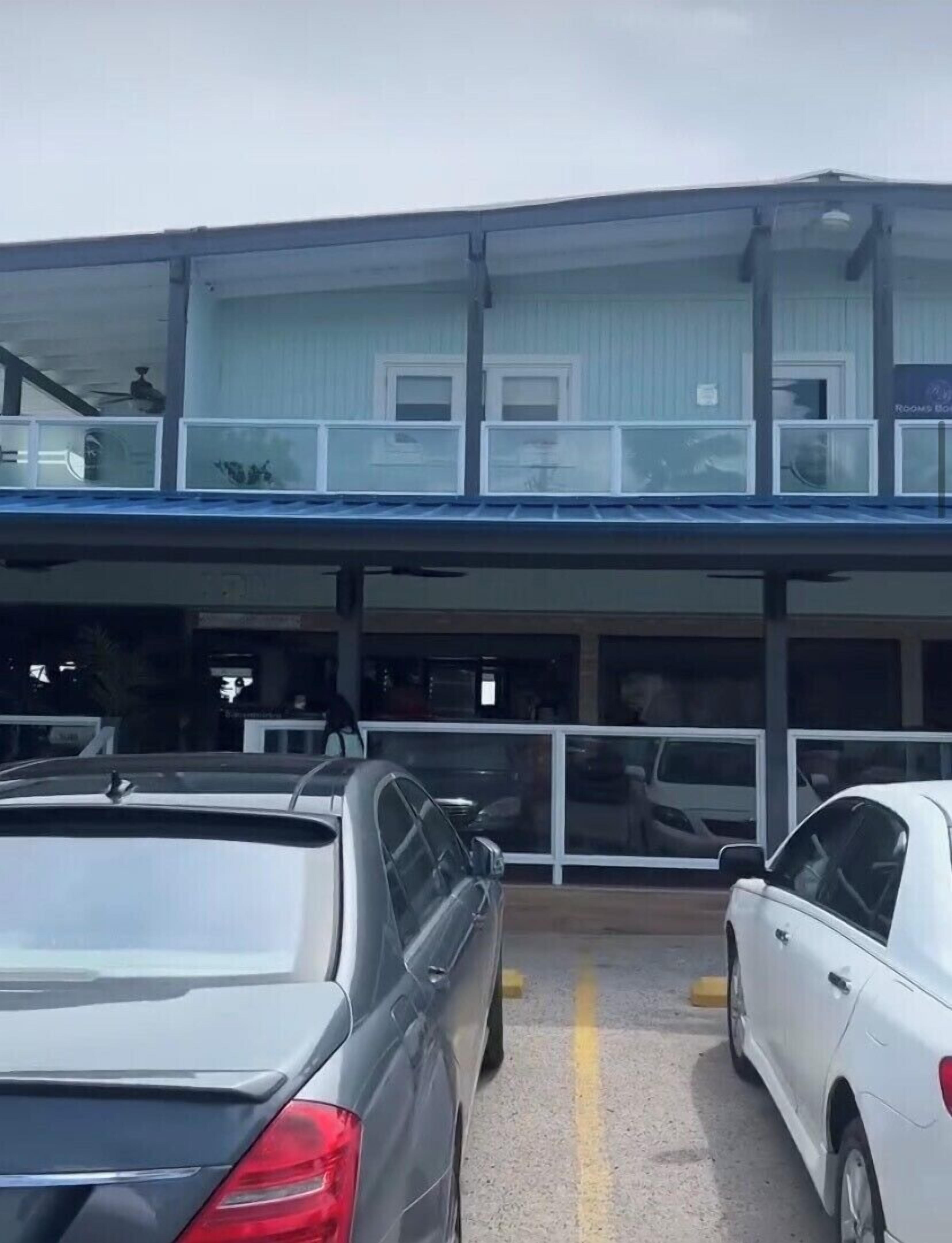 Ein Hotel mit zweistöckiger Bauweise, einer überdachten Eingangszone und einem Parkplatz für zwei Autos.