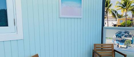Ein Zimmer mit einer hellblauen Wand, einer Holzbank, einem Holzstuhl und einem gerahmten Bild.