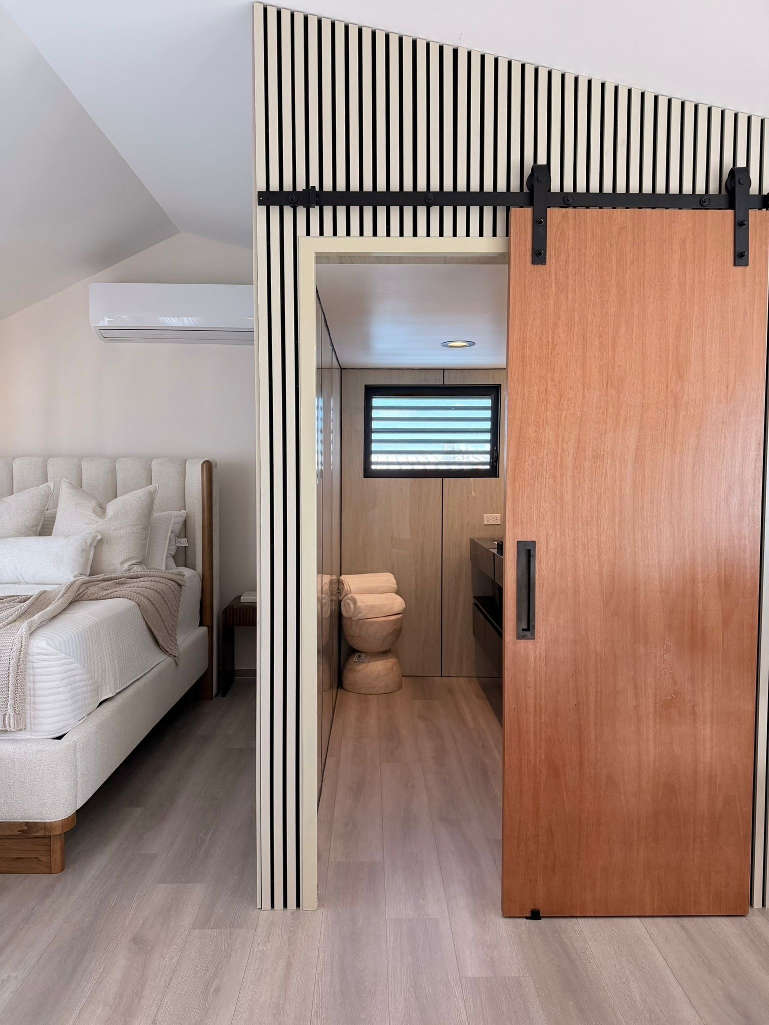 A modern bedroom with a bed, bedside table, and a built-in wardrobe with a sliding door.