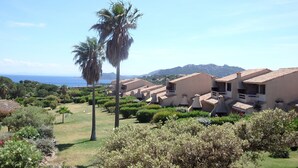 Un resort costero con edificios de tejas terracota, abundante vegetación y vistas al mar.