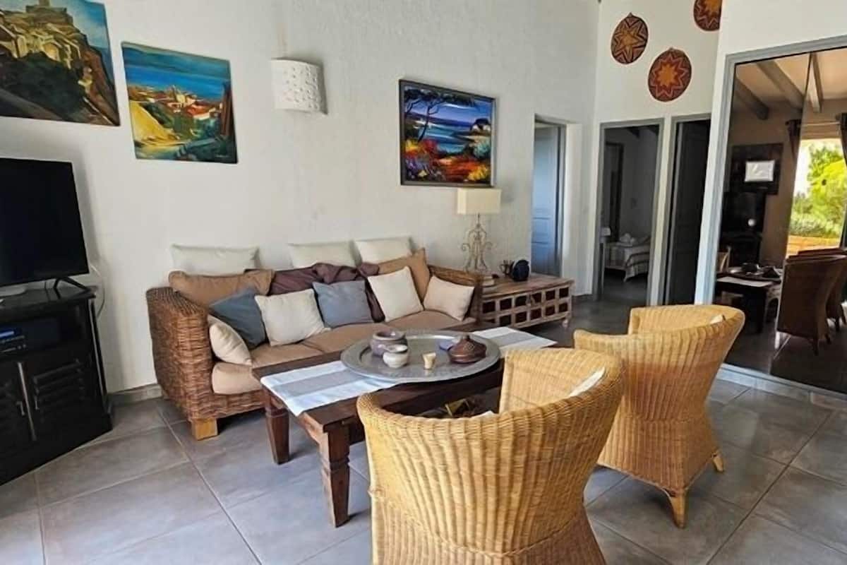 A living room with a sofa, two wicker chairs, a coffee table, and a TV.