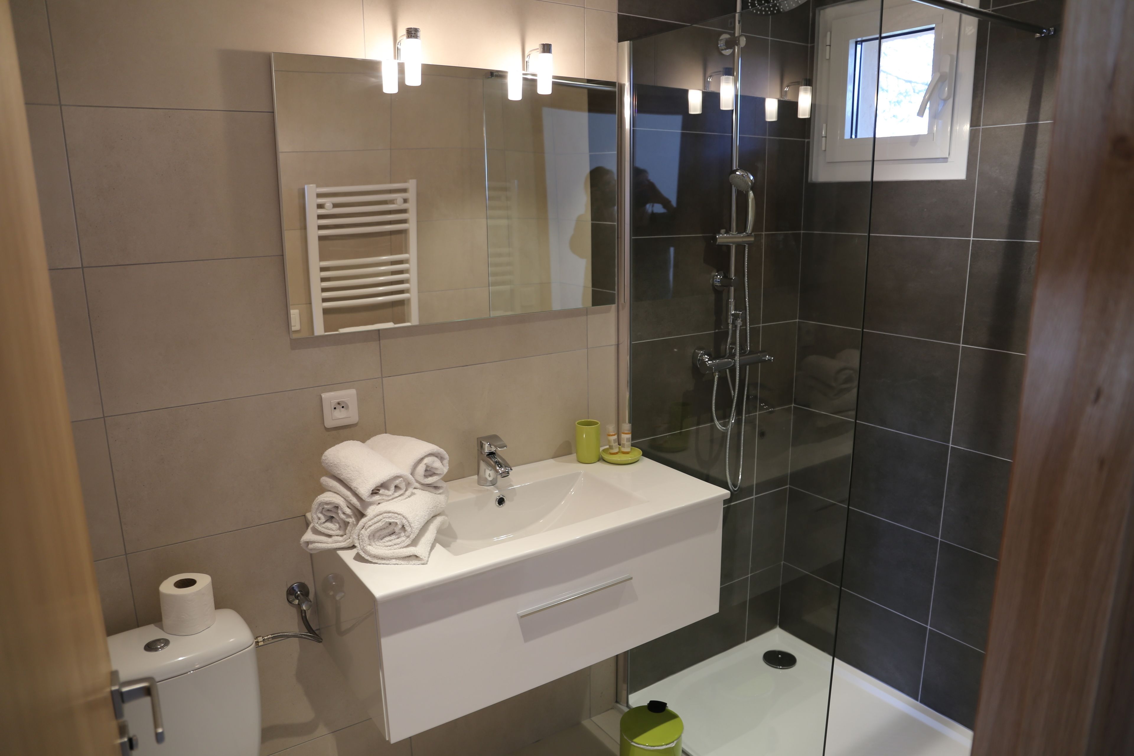 Un baño moderno con lavamanos, espejo y ducha blancos.