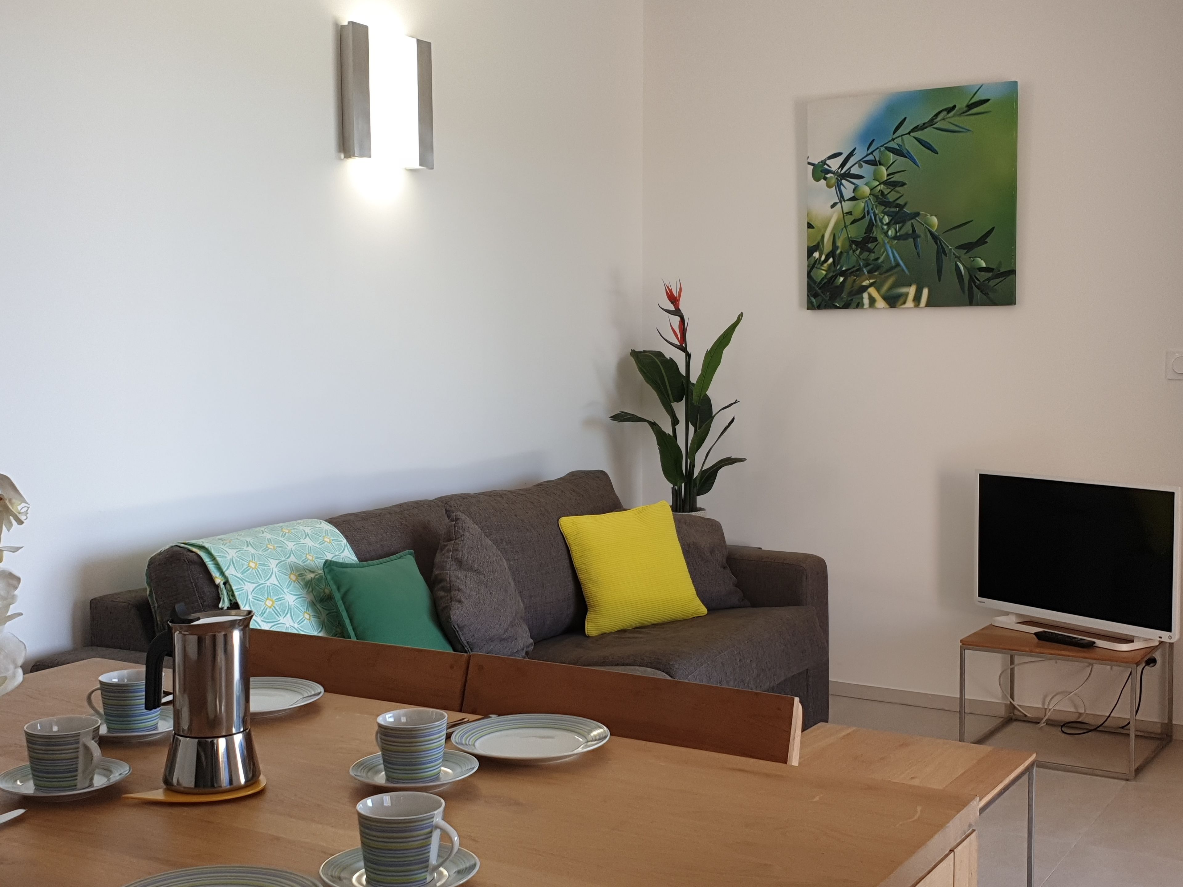 Ein modernes Wohnzimmer mit einer Couch, einem Couchtisch und einem Flachbildfernseher.