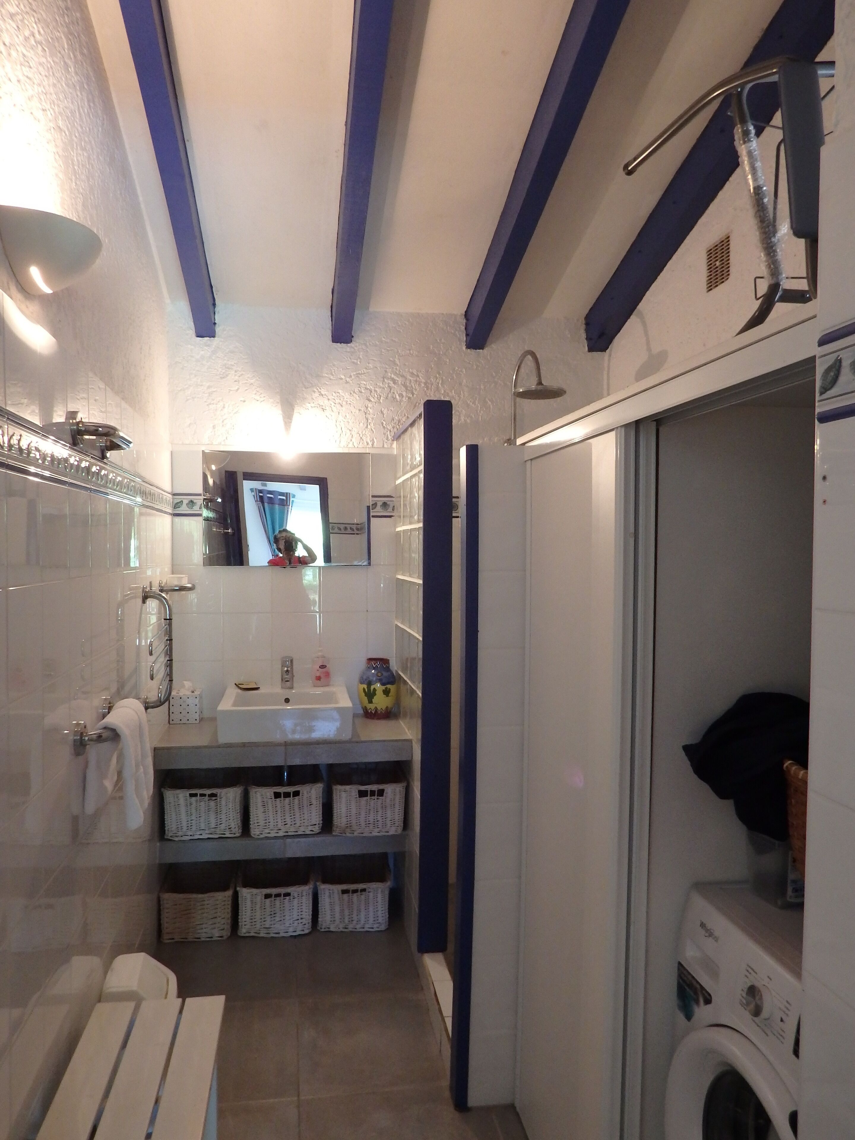 A compact bathroom with a shower, toilet, and washing machine.