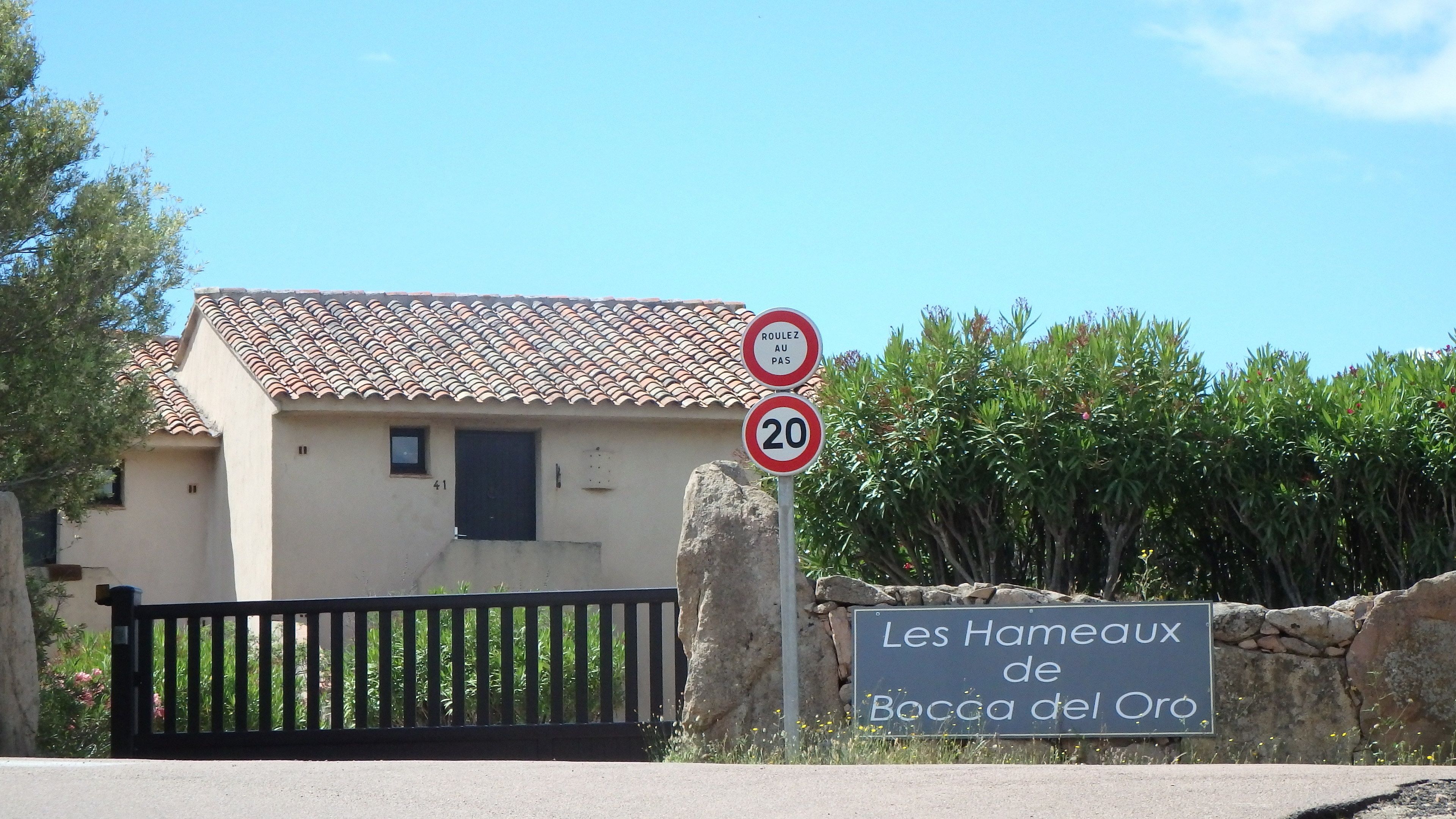 Una casa rural con tejado de tejas, una puerta y un cartel que indica 'Les Hameaux de Bocca del Oro'.