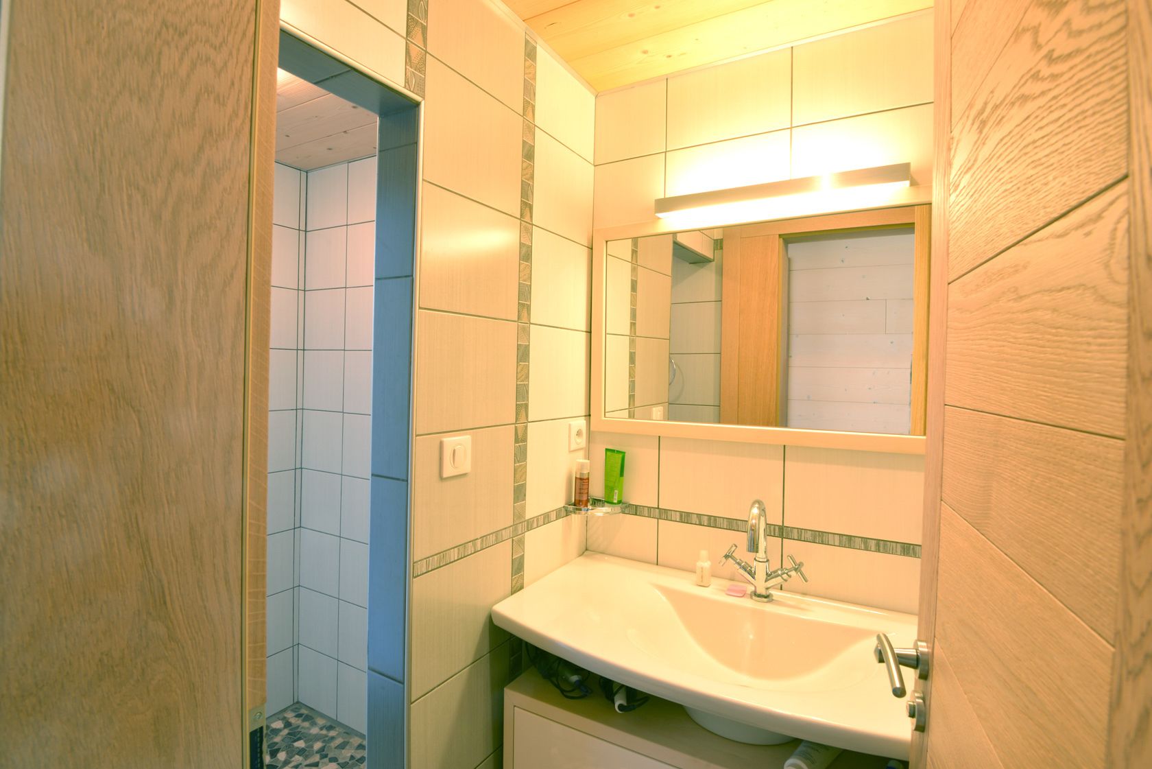 Een badkamer met een witte wastafel, een spiegel en een douche.
