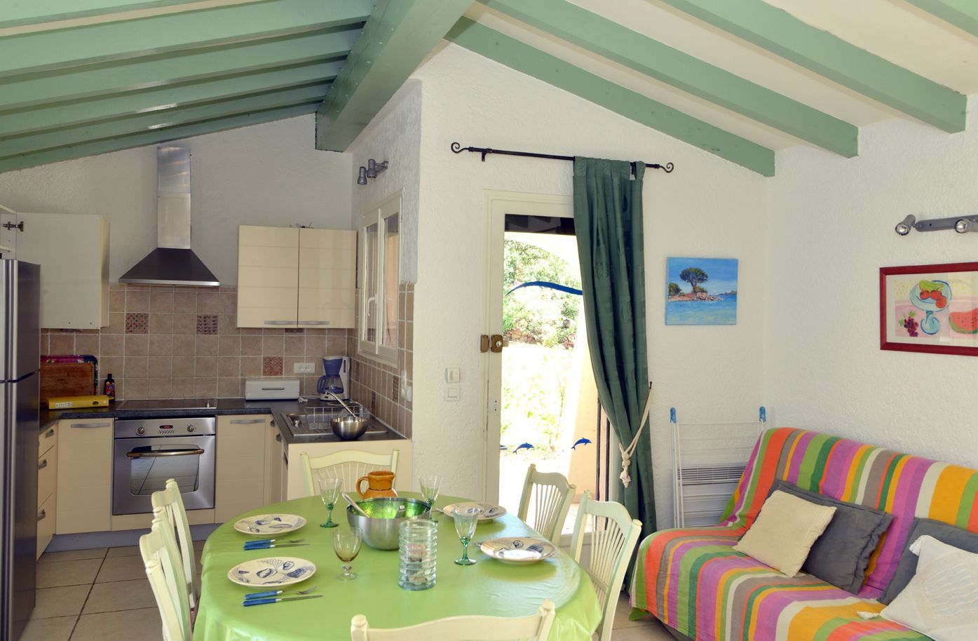A cozy kitchen with a dining area, a colorful sofa, and a view of the outdoors.