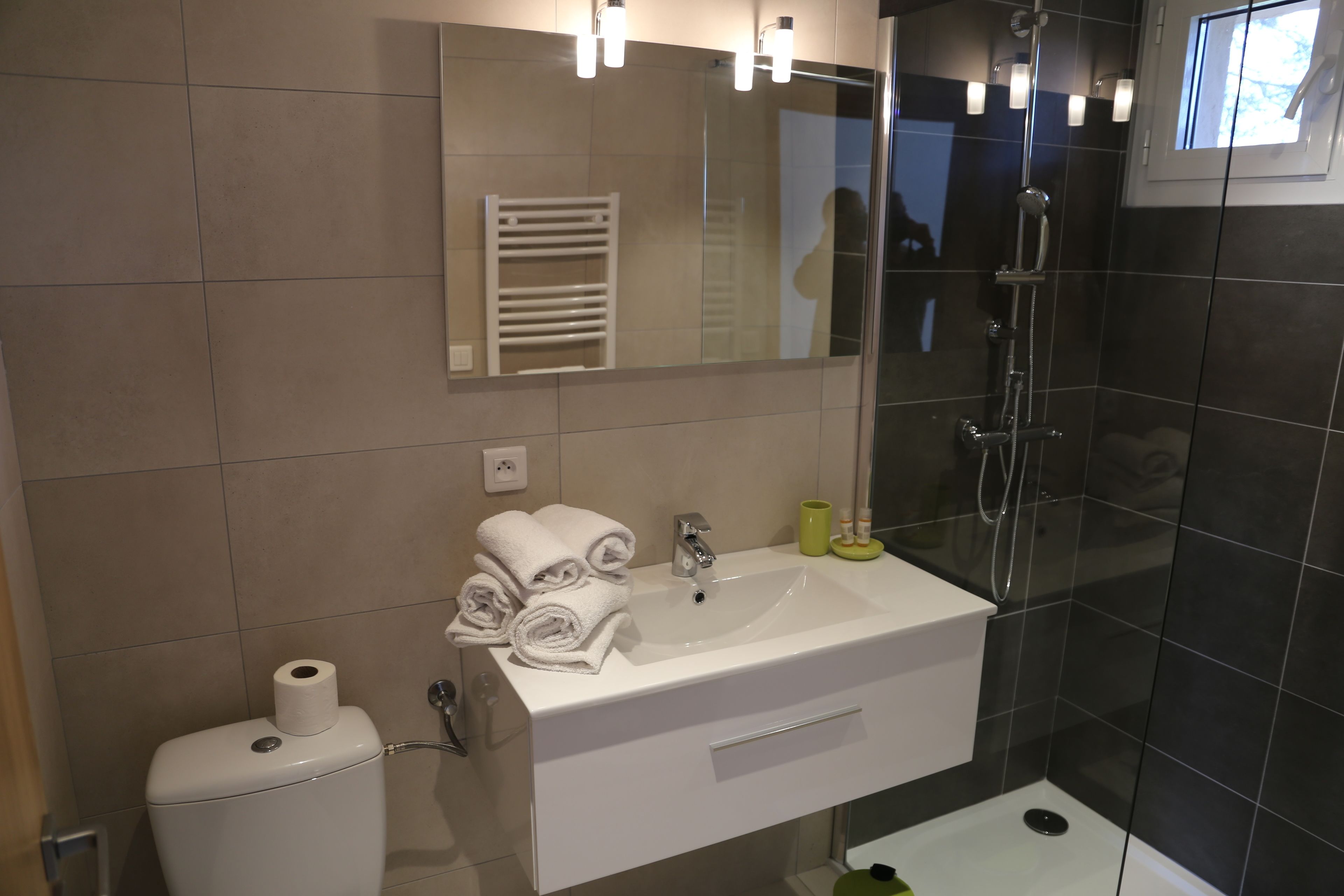 Un baño moderno con lavamanos blanco, inodoro y ducha con mampara de vidrio.