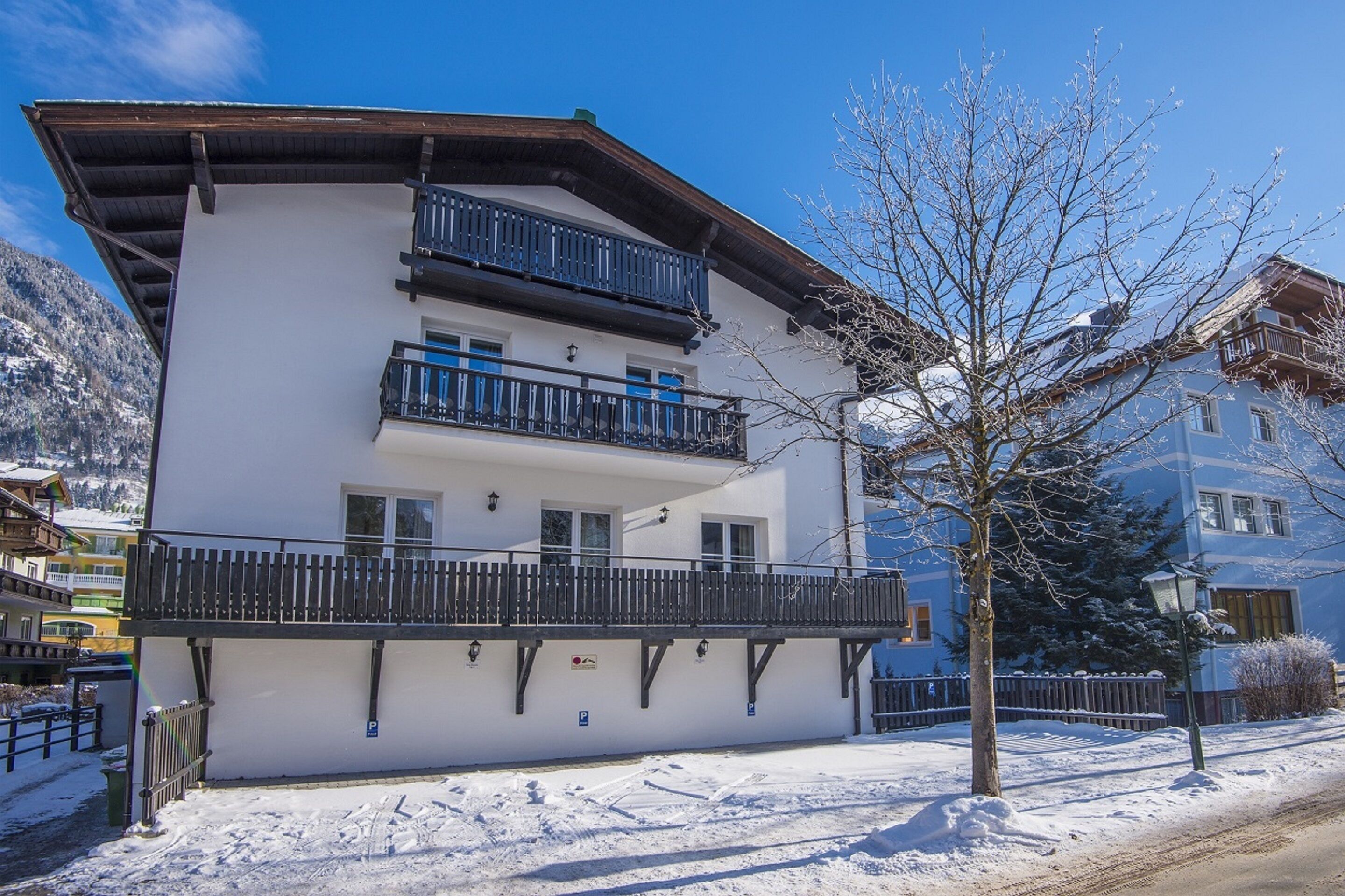 A two-story building with balconies, a snow-covered ground, and a clear blue sky.
