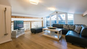 A modern living room with a television, a sofa, a coffee table, and a wooden floor. - Haus Wasmer by Alpentravel (Bad Hofgastein)