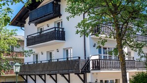 A multi-story building with balconies, a wooden deck, and a tree in the foreground. - Haus Wasmer by Alpentravel (Bad Hofgastein)