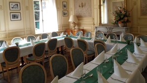 Een formele eetzaal met een lange tafel gedekt voor een maaltijd, omringd door stoelen.