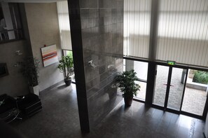 Experience the grandeur of our lobby, featuring a high ceiling, reception desk, and beautiful artwork.