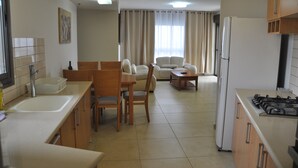 A compact kitchen with a dining area, a refrigerator, and a stove.