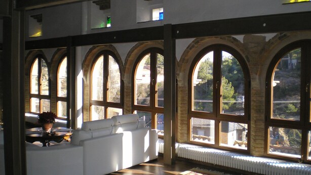 A room with a white sofa, large arched windows, and a radiator. - Ca L'Estruch (Vallclara)