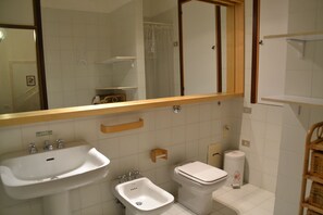 Un baño con lavamanos, bidé, inodoro y espejo.