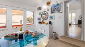 A modern kitchen with a dining area, featuring a glass table, white cabinets, and various kitchen appliances. - Apartments Subrenum (Zupa dubrovacka)